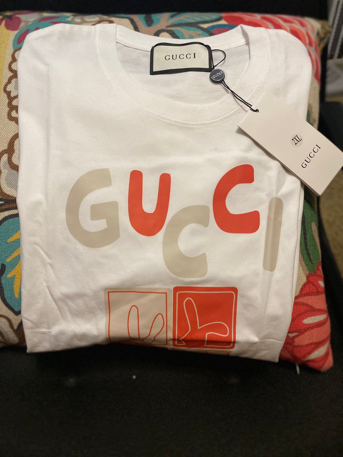 White Gucci t-shirt with colorful text and logo on a patterned surface