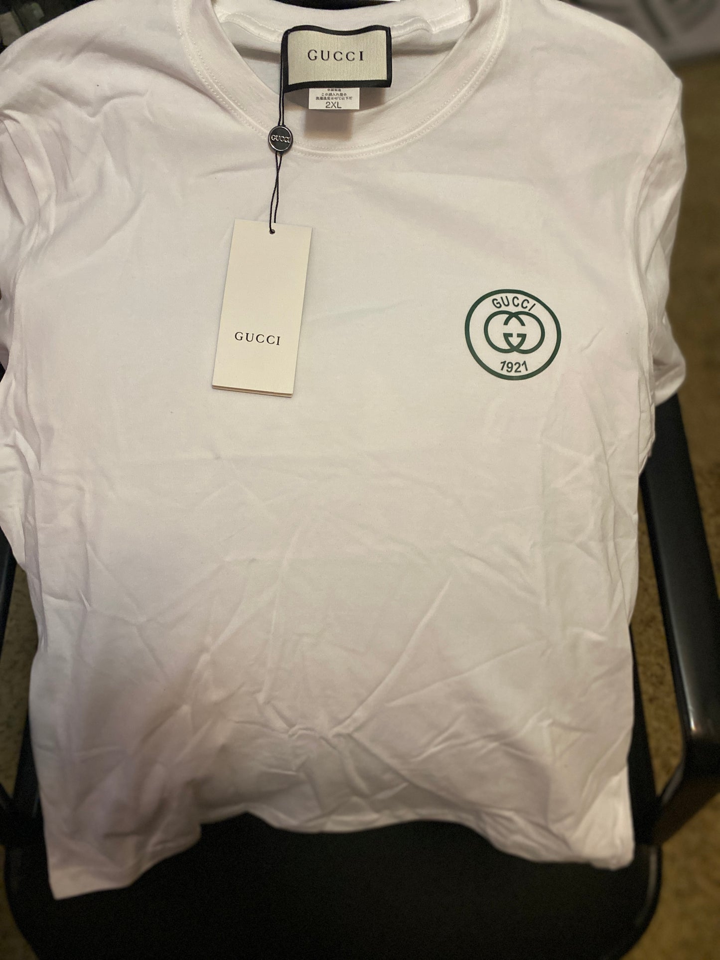 White Gucci t-shirt with a logo and tag on a black surface