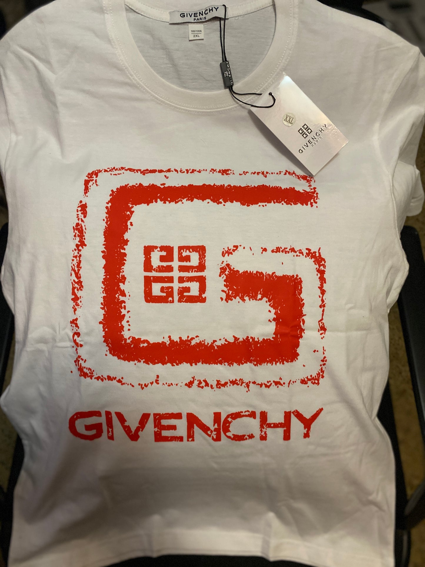 White Givenchy t-shirt with red logo and tag on a plain background