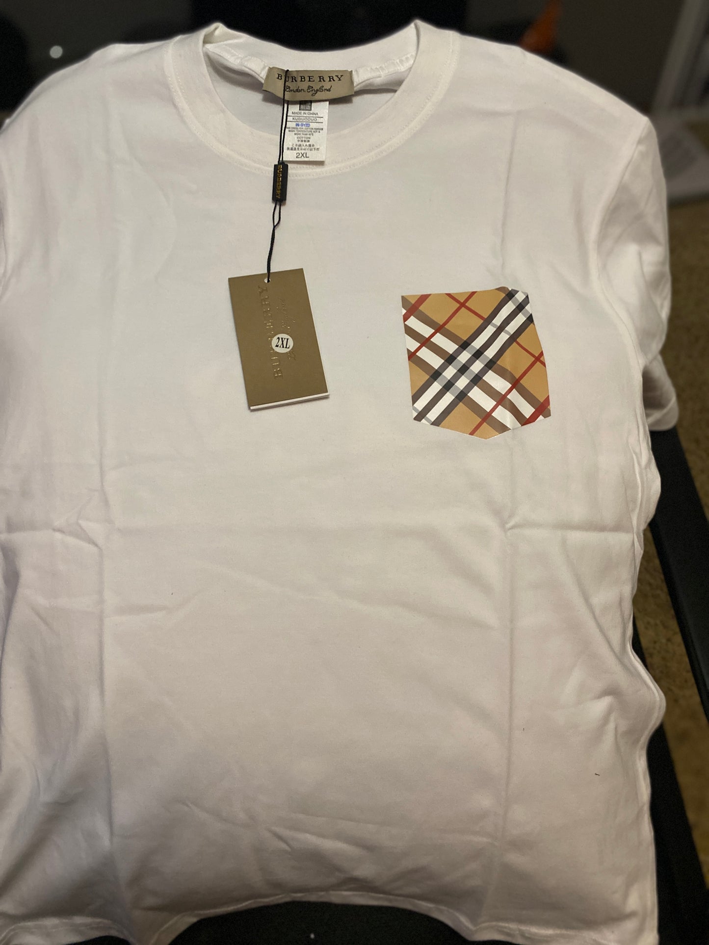 White shirt with a plaid pocket and Burberry tag on a dark background